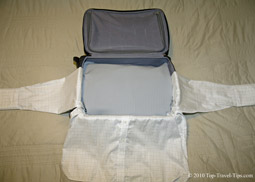 Shirts being wrapped around packing cube as part of bundle wrapping packing